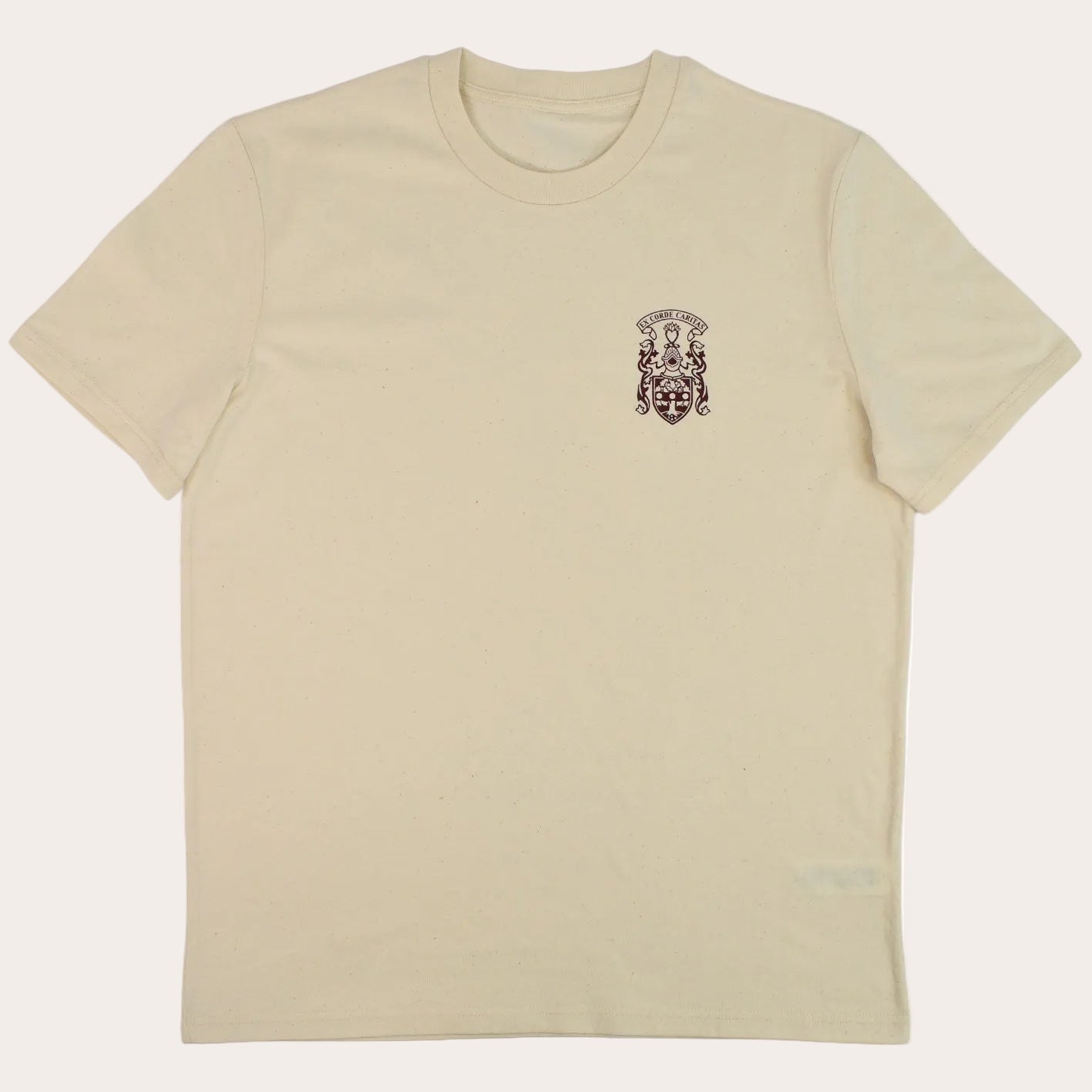 A cream-colored short-sleeve crewneck t-shirt with a small dark red crest graphic printed on the left chest, displayed flat against a white background.